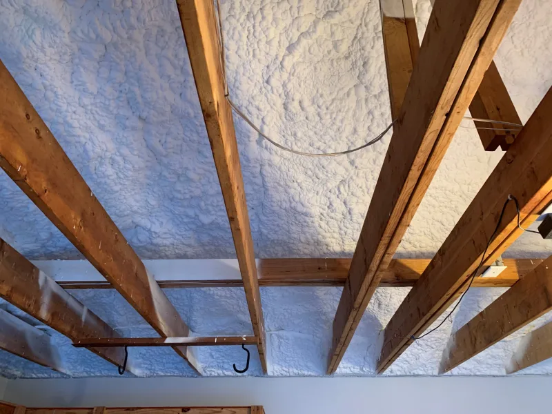 White ignition barrier coating sprayed over spray foam between ceiling joists