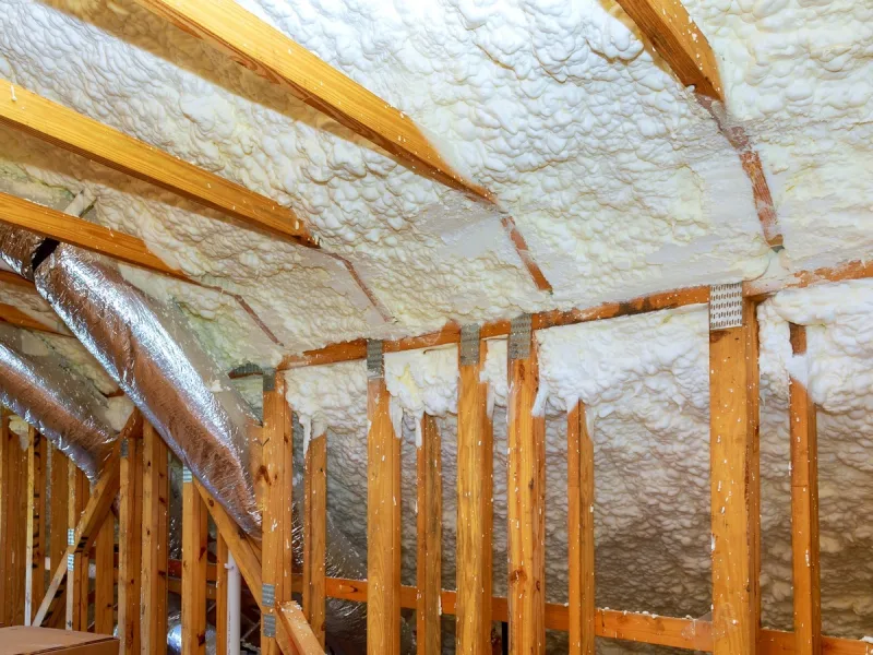 Open-cell foam installed between attic rafters, showing installed depth